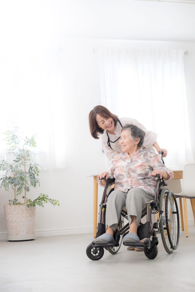 elderly asian woman in a wheelchair with a nurse carer pushing her smiling